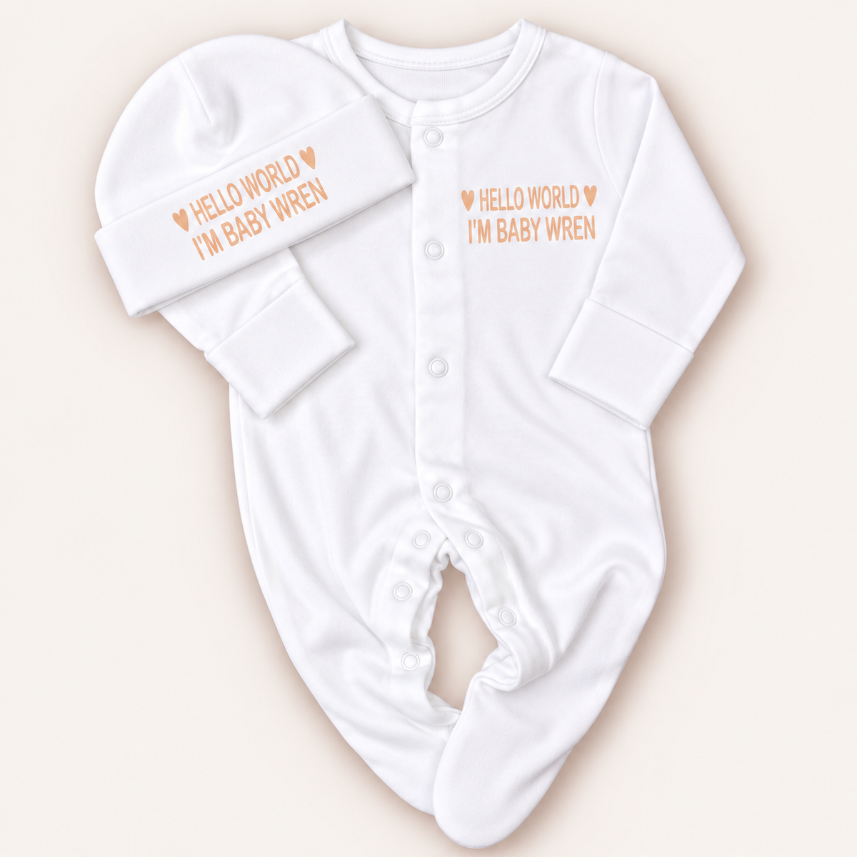 White personalised Hello World baby grow and matching hat with neutral lettering and heart details, Grace & Grayson