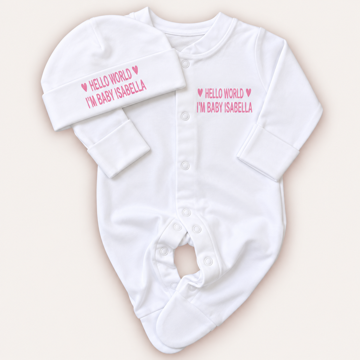 White personalised Hello World baby grow and matching hat with pink lettering and heart details, Grace & Grayson