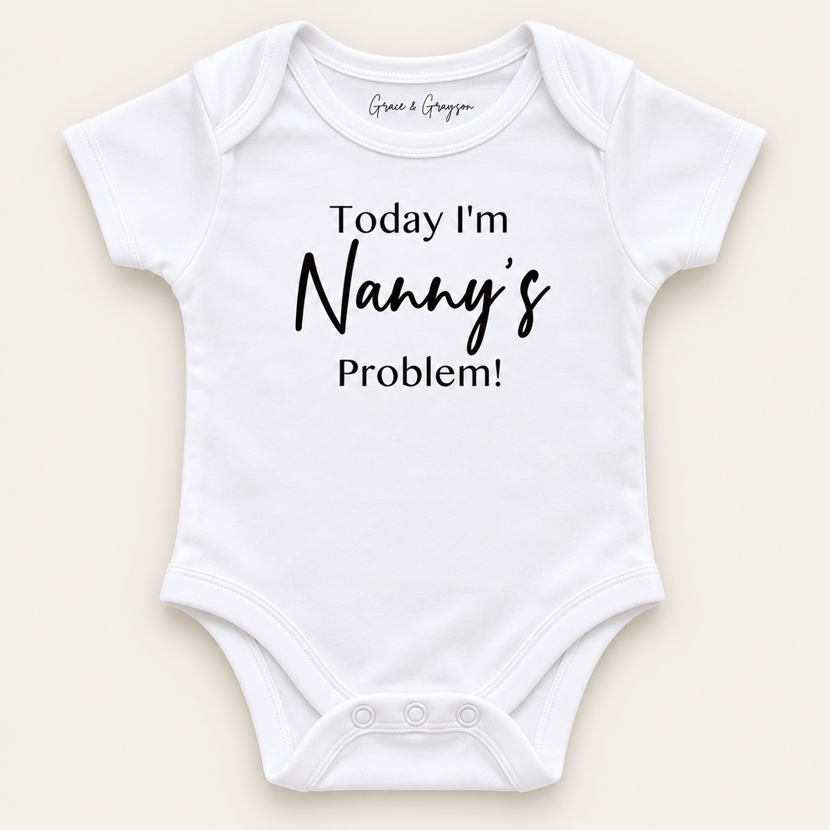White personalised baby vest with black lettering reading “Today I’m Nanny’s Problem!”, displayed on a light background, Grace & Grayson.