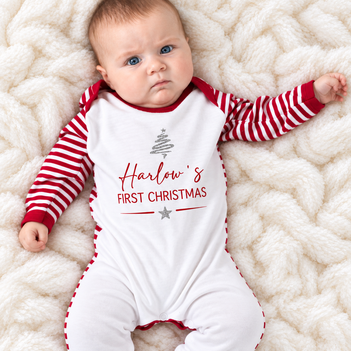 Baby wearing a personalised First Christmas red and white stripe baby grow with a silver Christmas tree design, Grace & Grayson