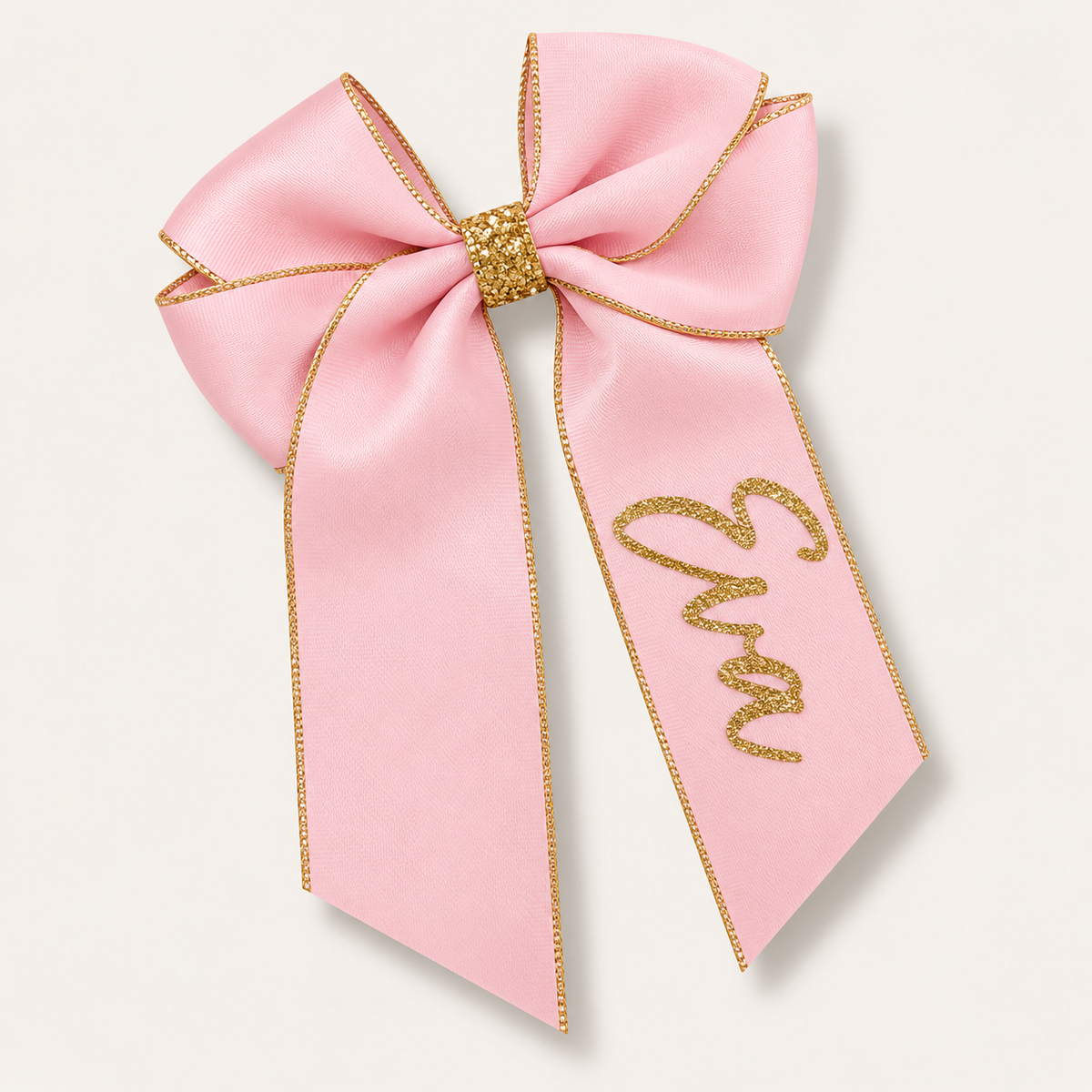Light pink satin hair bow with gold trim, a gold centre wrap and gold glitter lettering, Grace & Grayson.