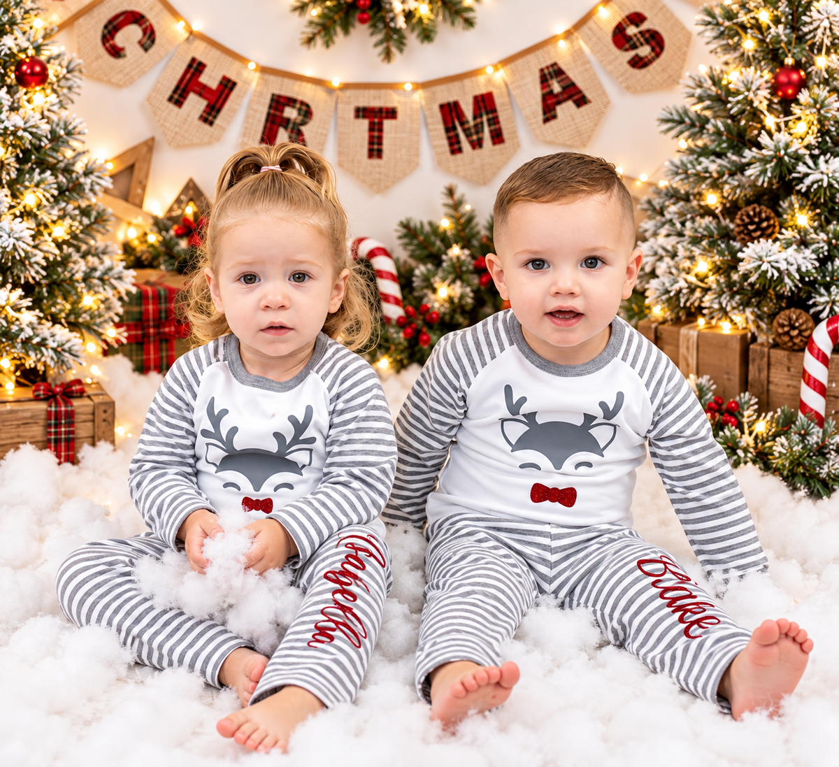 Two children wearing personalised grey stripe Christmas reindeer pyjamas in a festive Christmas setting, Grace & Grayson