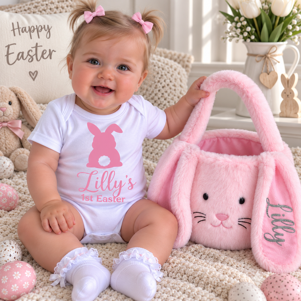 Baby wearing a white personalised 1st Easter vest with a pink bunny design, beside a pink Easter basket, Grace & Grayson
