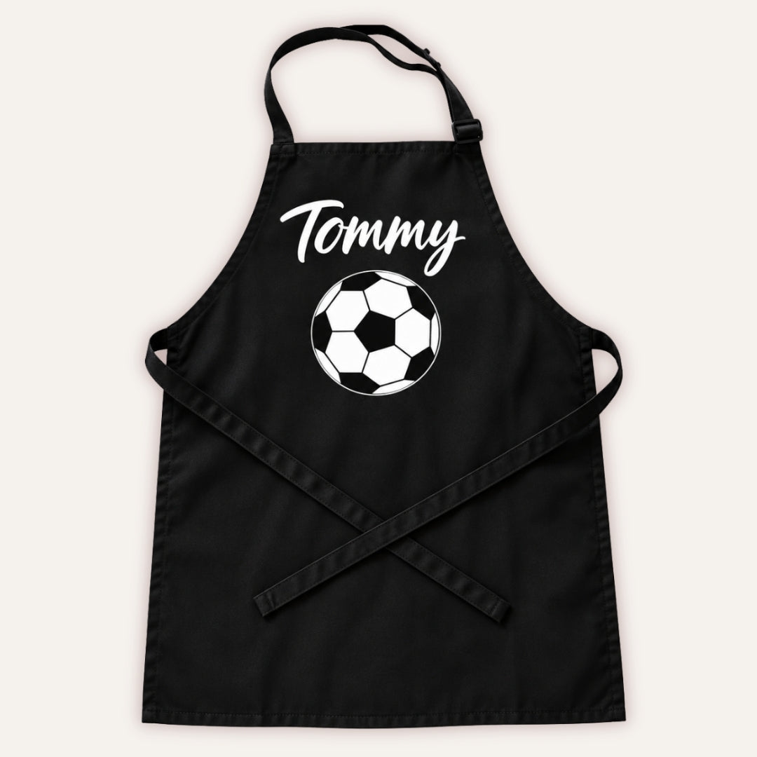 Black personalised children’s apron with white football design on a white background, Grace & Grayson