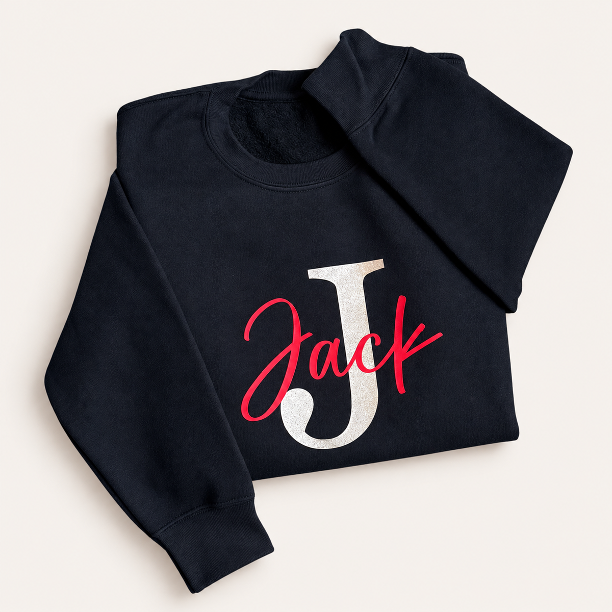 Black personalised sweatshirt with a silver initial and red script name, laid flat | Grace & Grayson