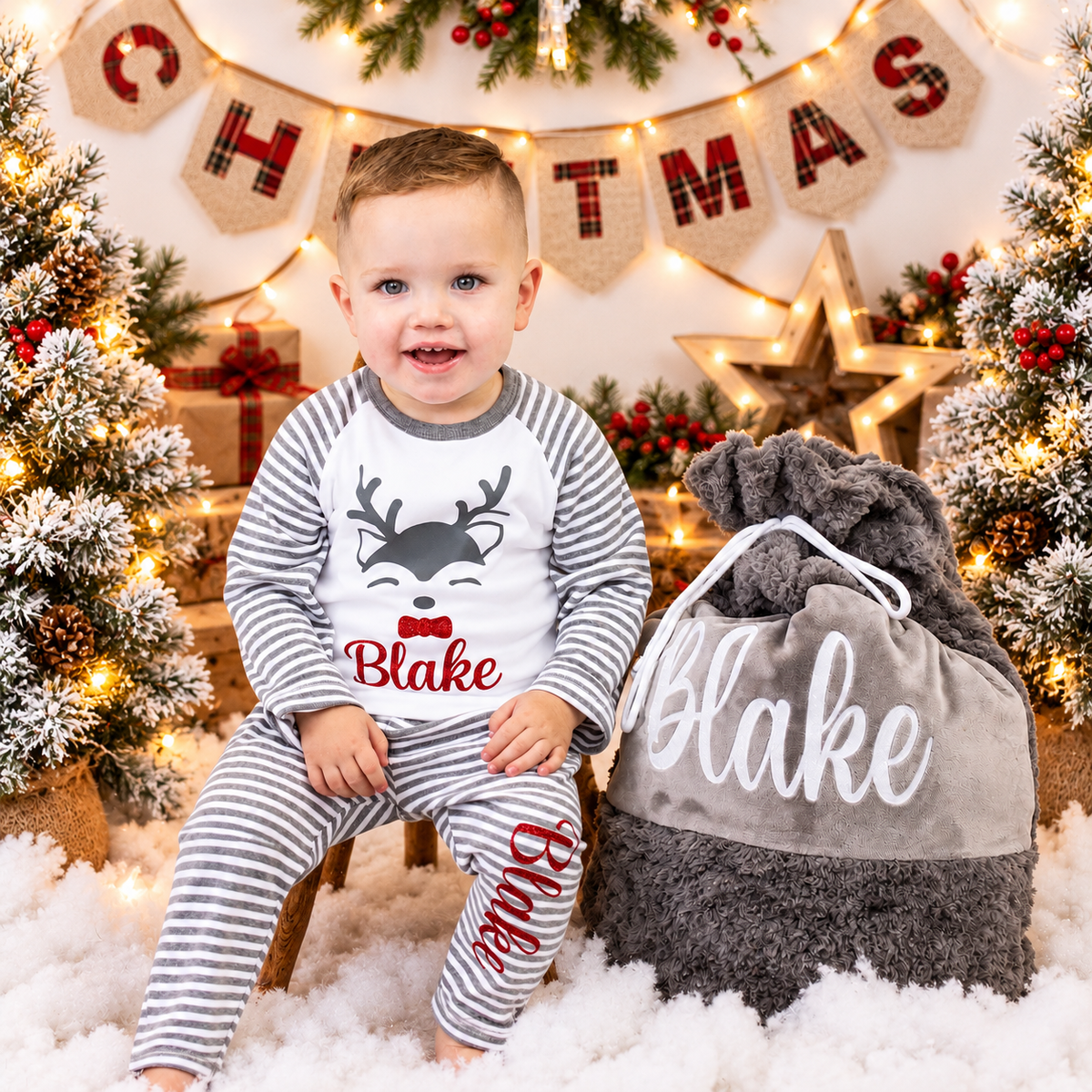 Child wearing personalised grey stripe Christmas reindeer pyjamas in a festive Christmas setting, Grace & Grayson