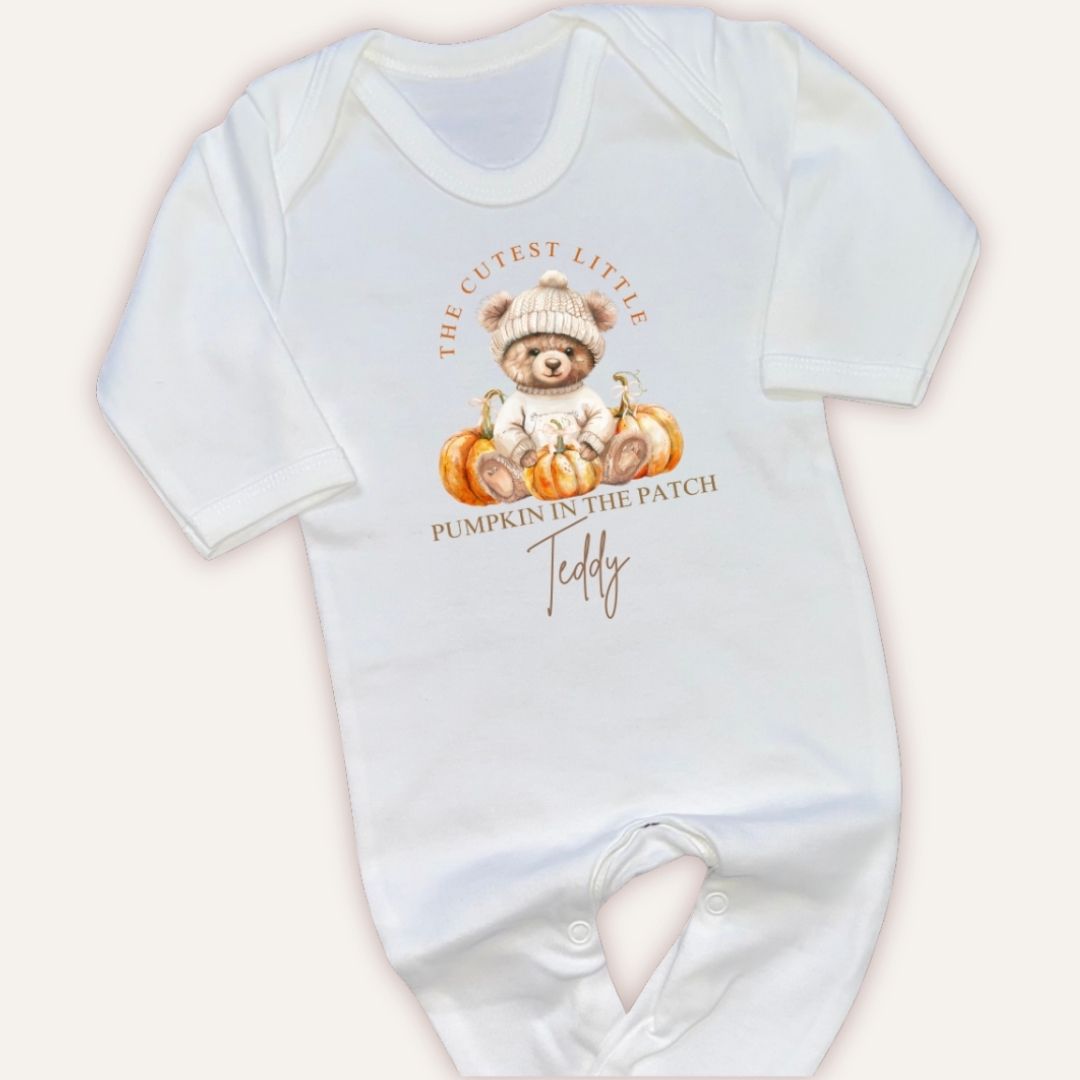 Close-up flat lay of personalised pumpkin in the patch white baby grow with pumpkin bear design and custom name, Grace & Grayson