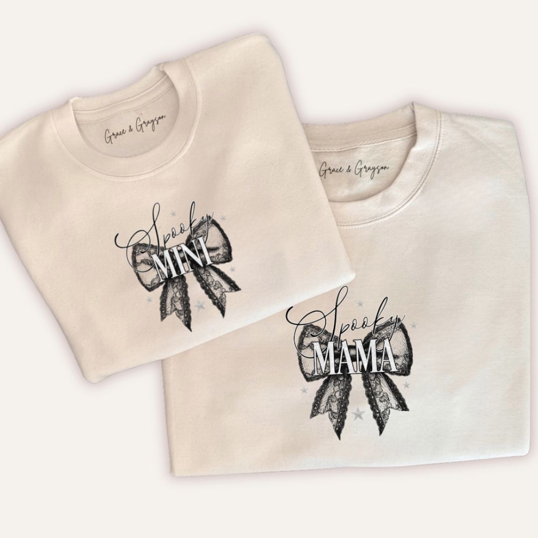 Folded personalised Spooky Mama and Mini Halloween bow sweatshirts in white showing spooky lace bow design by Grace & Grayson