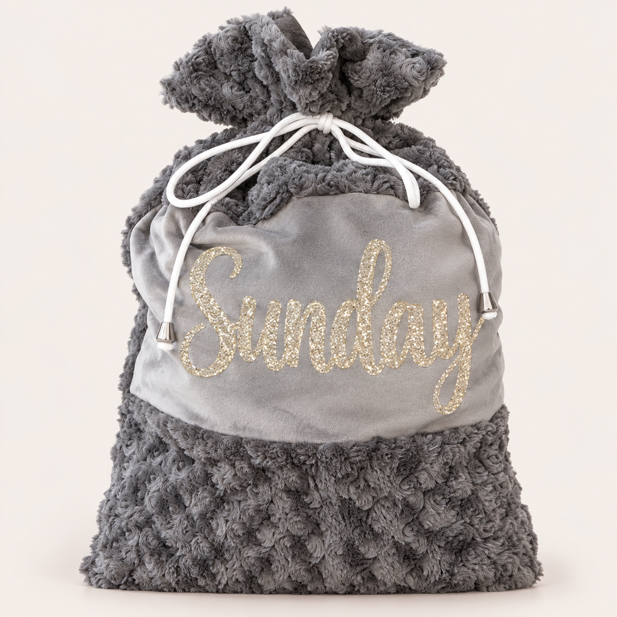 Grey plush Christmas Santa sack with gold glitter lettering and white drawstrings against a light background, Grace & Grayson.