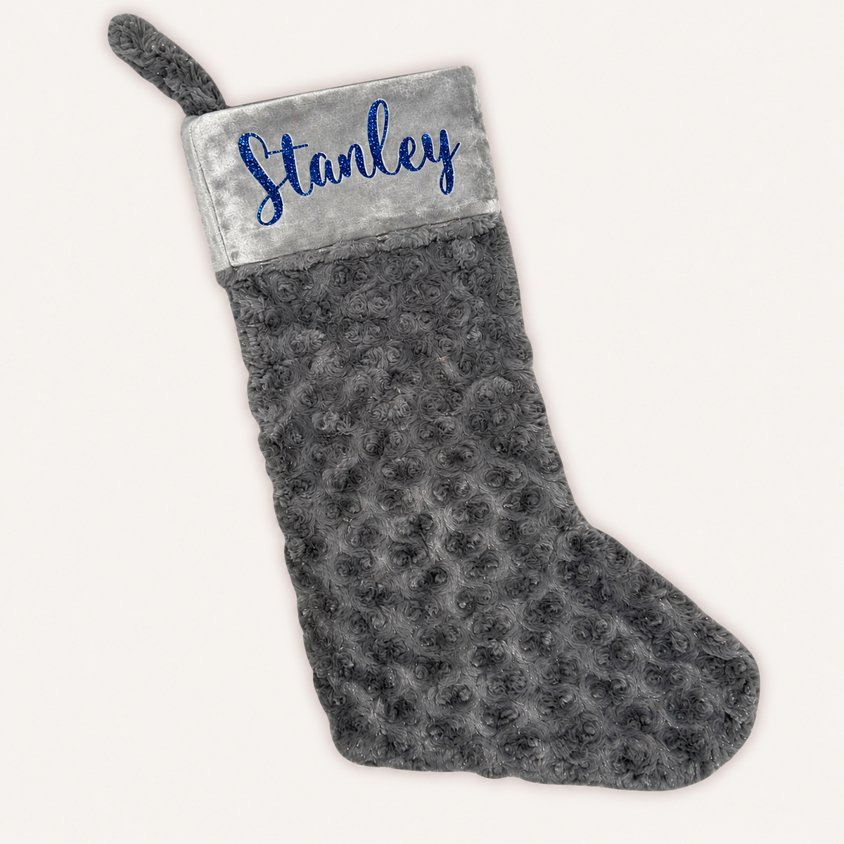 Grey plush Christmas stocking with a grey cuff, blue glitter personalised lettering and a hanging loop, Grace & Grayson.