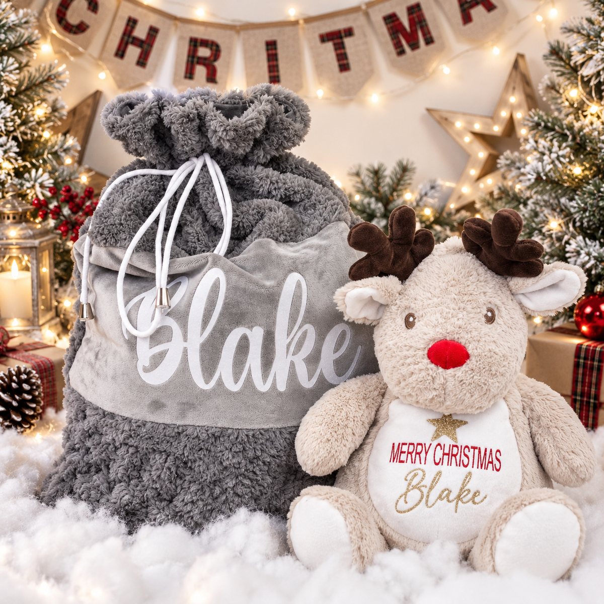 Light brown reindeer Christmas teddy beside a grey personalised Christmas sack and decorated Christmas tree, Grace & Grayson