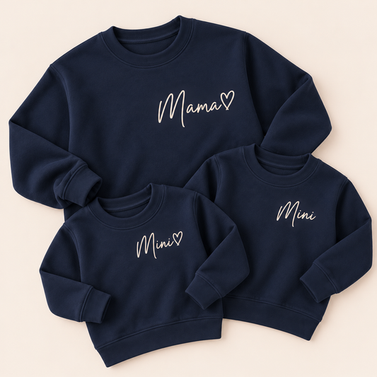 One adult Mama and two children’s Mini navy sweatshirts with white script lettering, laid flat together | Grace & Grayson