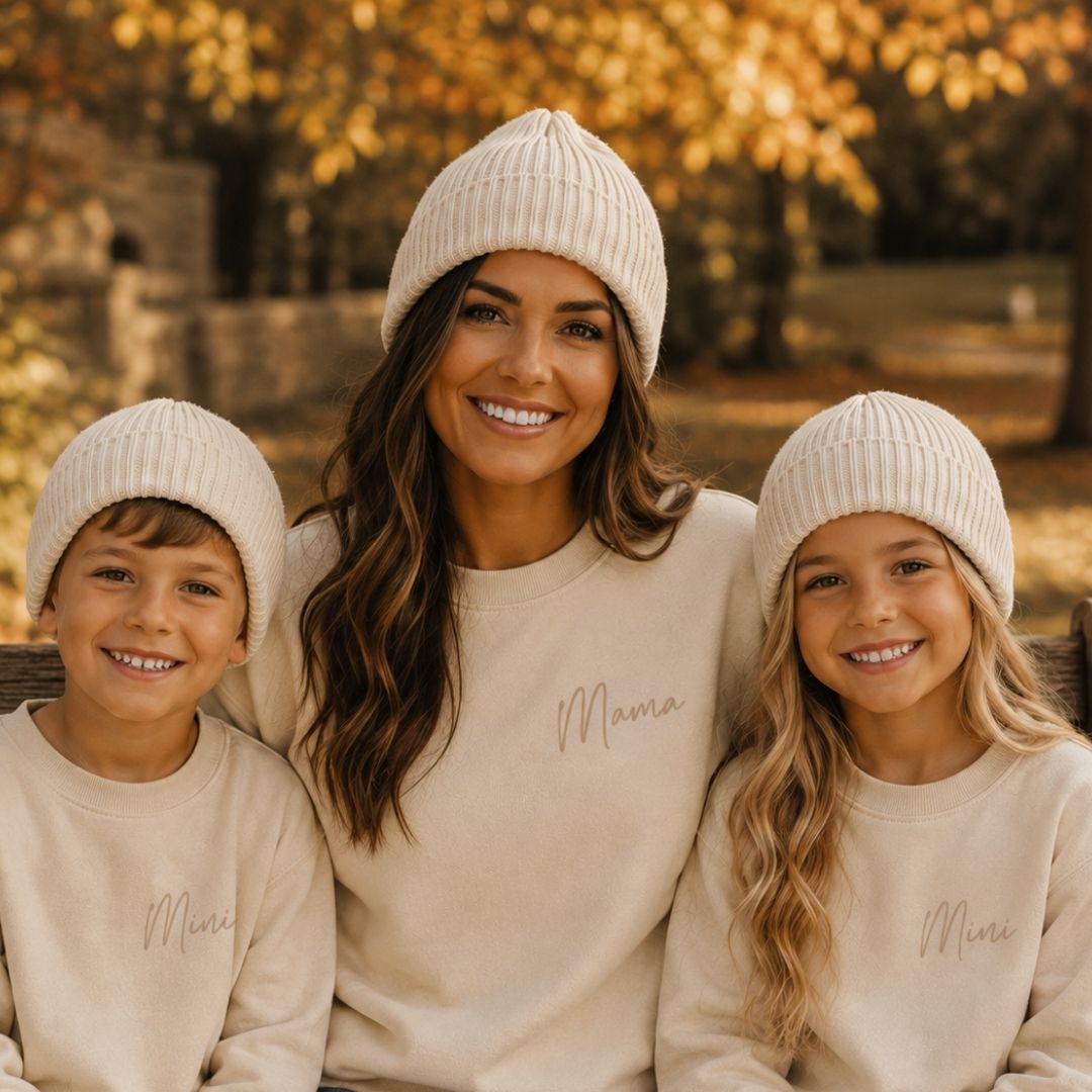 Mum and two children wearing matching ribbed knit beanie hats in nude, sitting outdoors in autumn by Grace & Grayson