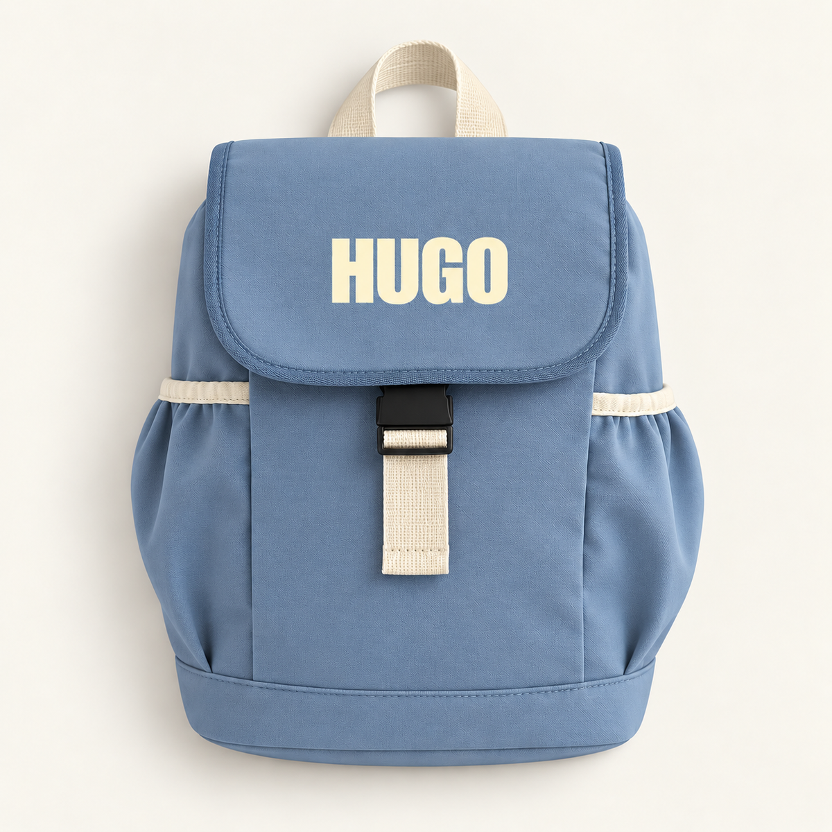 Dusty blue personalised children’s backpack with cream block lettering, side pockets and a buckle fastening, Grace & Grayson.