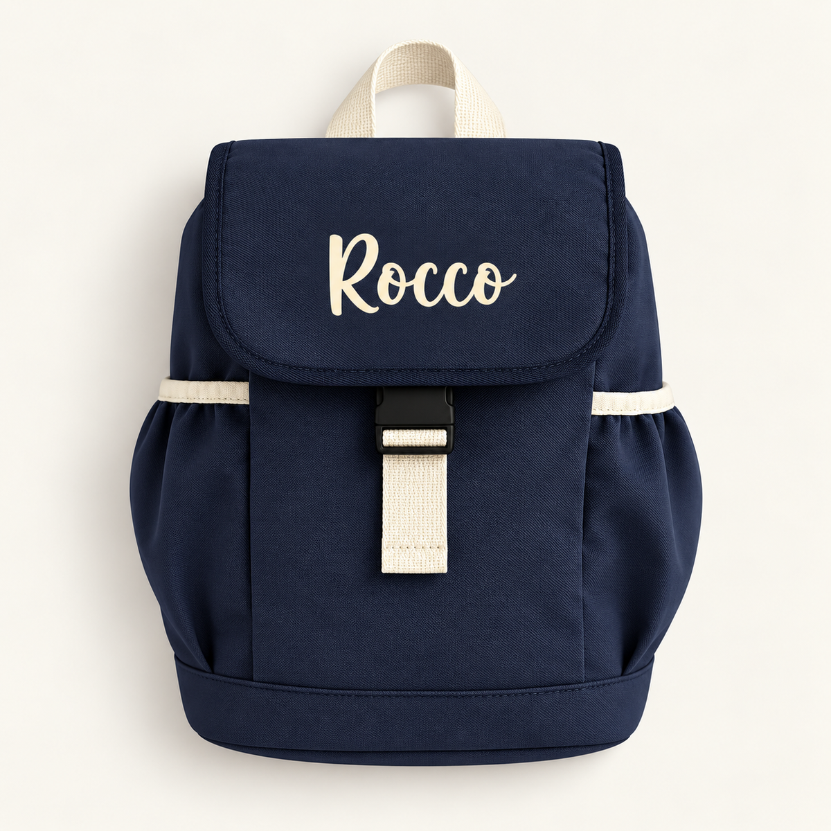 Navy personalised children’s backpack with cream script lettering, side pockets and a buckle fastening, Grace & Grayson.