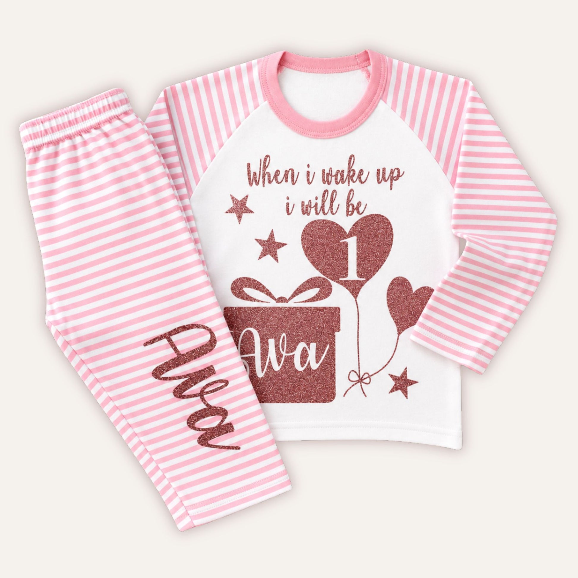 Personalised girls 1st birthday pink striped pyjamas featuring glitter birthday design, heart balloon number 1, custom name and matching striped trousers.