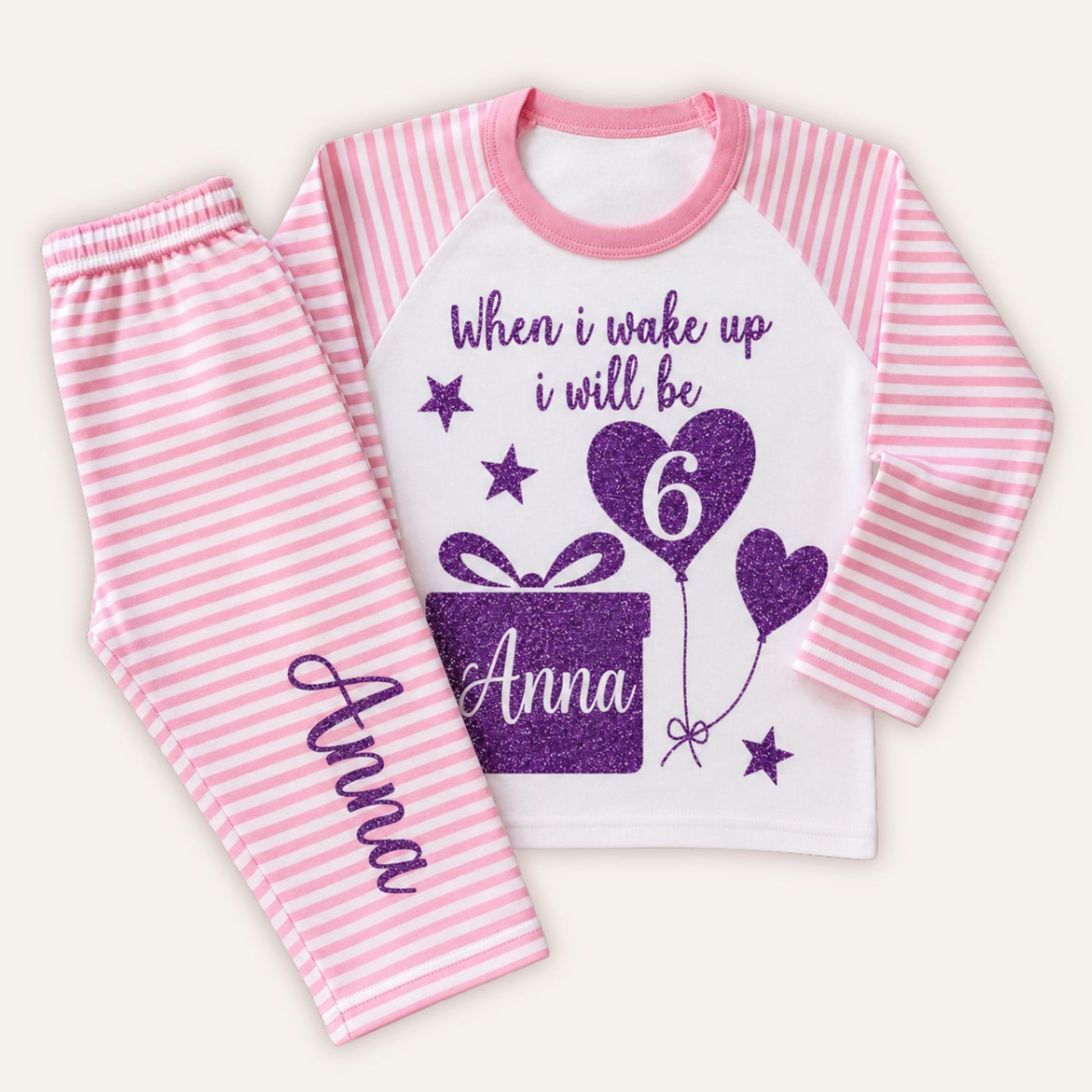 Personalised girls 6th birthday pink striped pyjamas with purple glitter birthday design, heart balloon number 6, gift box graphic and custom name.