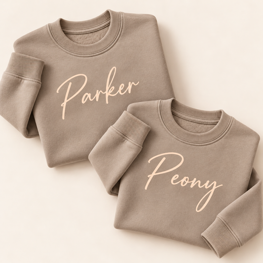 Two  personalised mink sweatshirts with cream script names, folded on a beige background | Grace & Grayson”ink