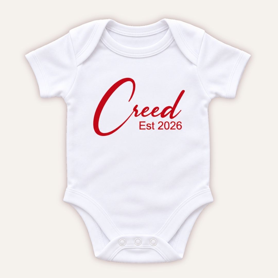 Personalised EST baby vest in red pearl featuring a baby’s name and year of birth, Grace & Grayson.
