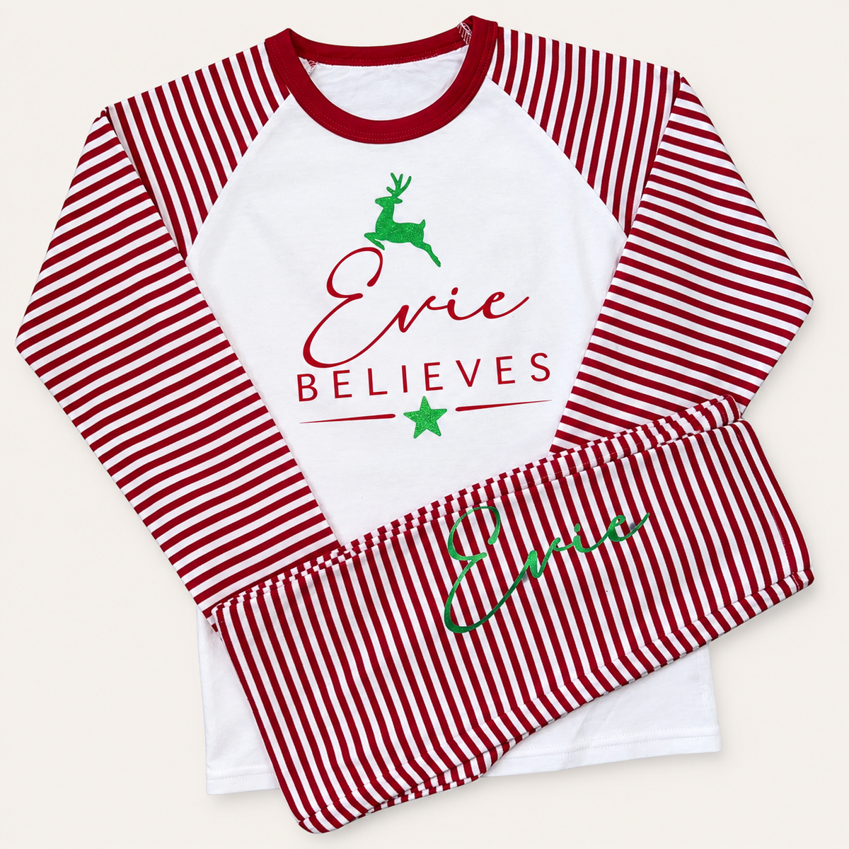Red and white striped personalised Believes Christmas pyjamas shown as a coordinated set with green and red festive designs, Grace & Grayson