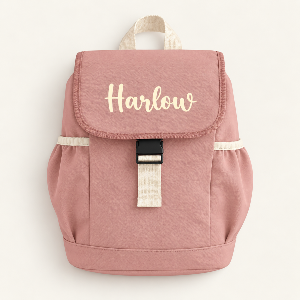 Rose pink personalised children’s backpack with cream script lettering, side pockets and a buckle fastening, Grace & Grayson.