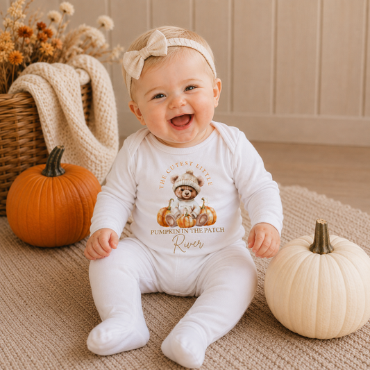 Smiling baby wearing personalised cutest little pumpkin in the patch white baby grow, surrounded by pumpkins, Grace & Grayson