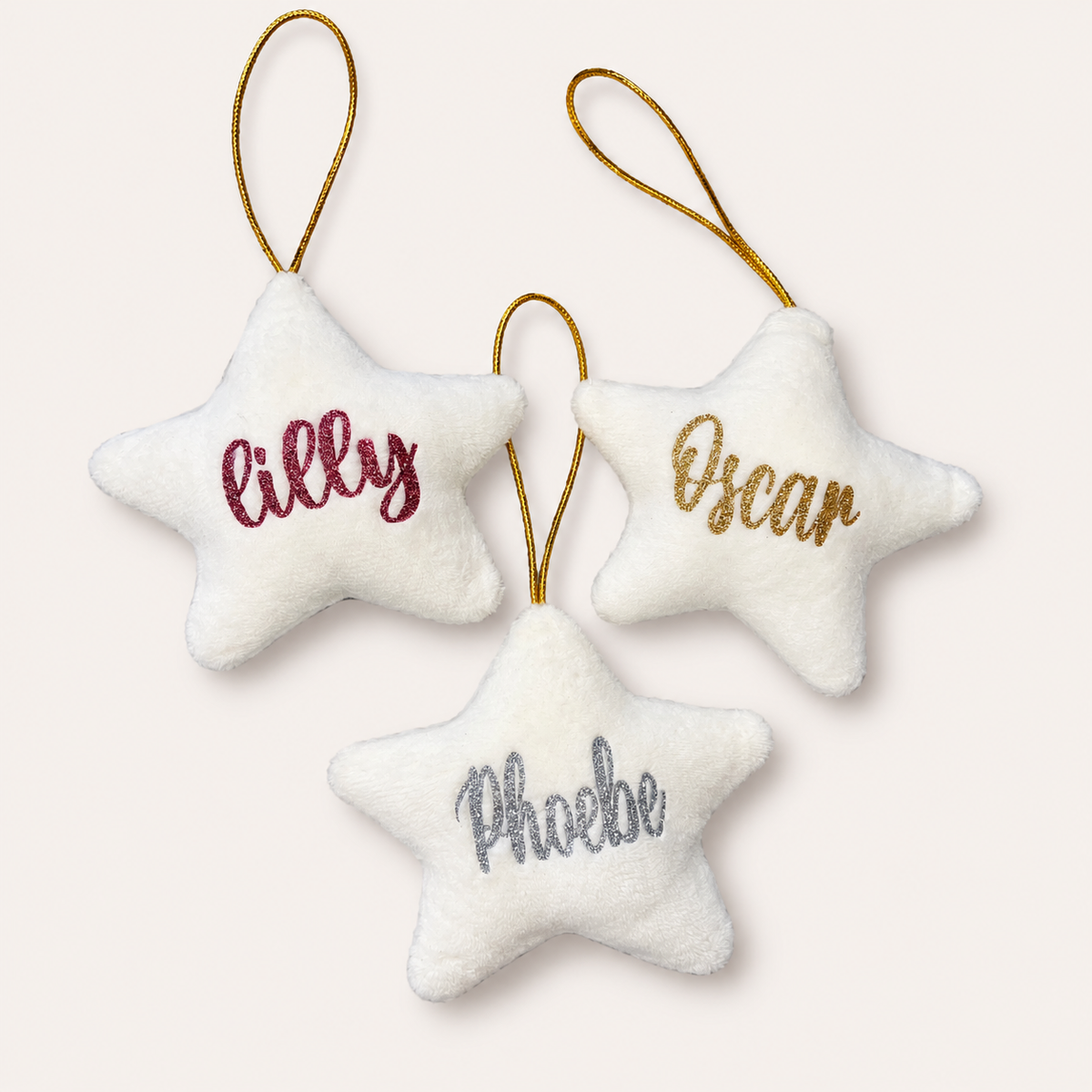 Three white personalised Christmas star tree decorations with red, gold and silver glitter lettering, displayed together, Grace & Grayson