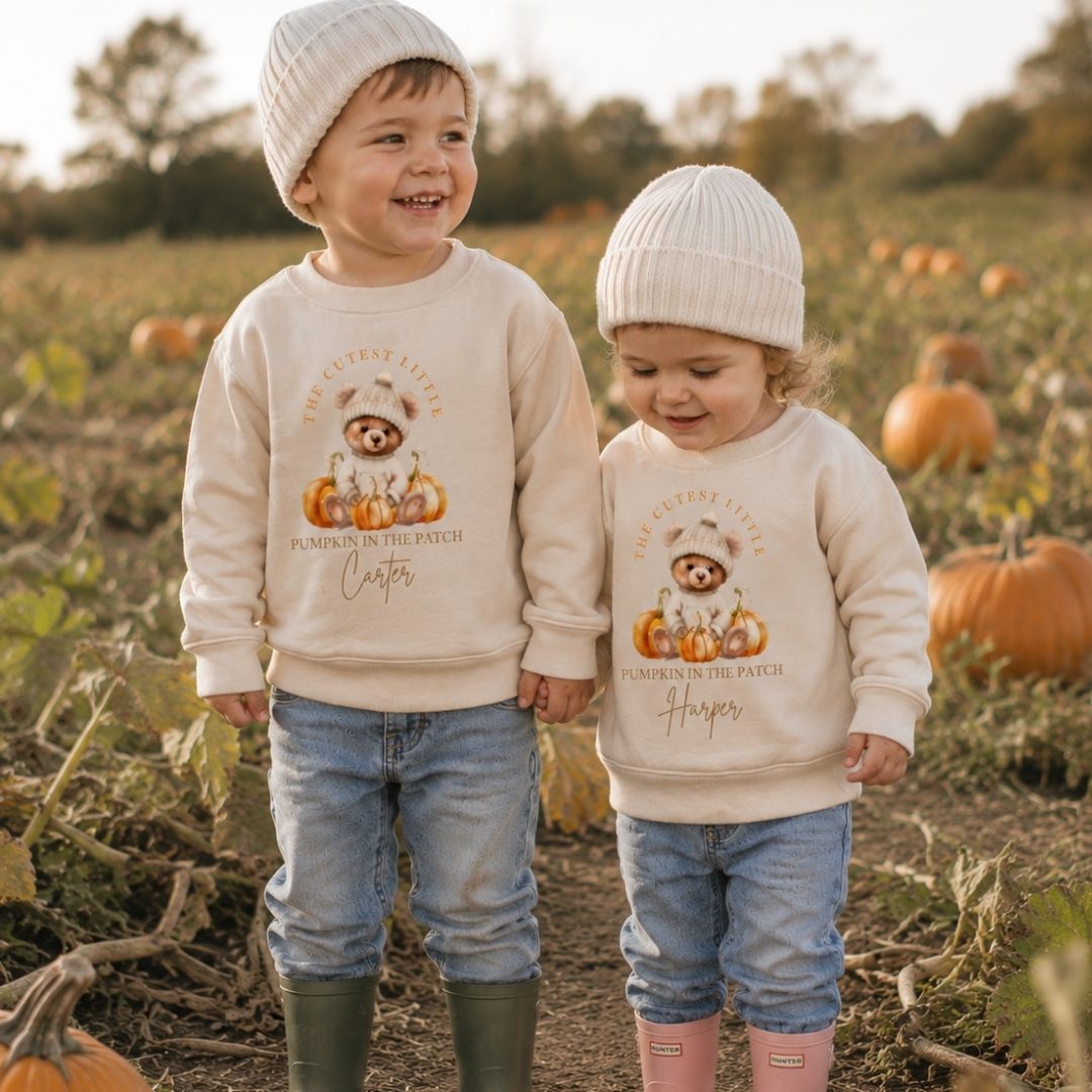 Two children wearing personalised cutest little pumpkin in the patch sweatshirts in a pumpkin patch, Grace & Grayson