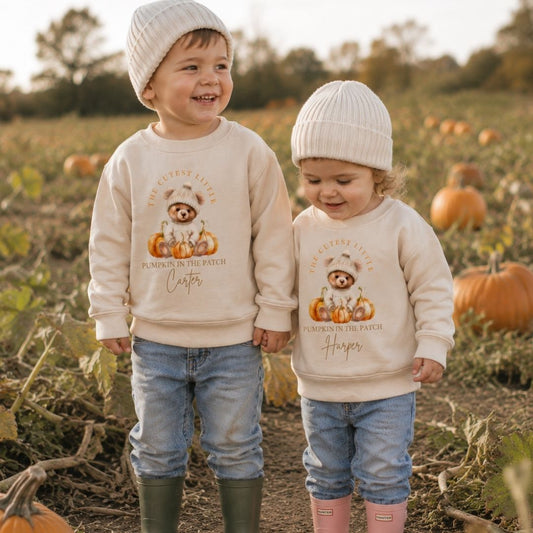 Two children wearing personalised cutest little pumpkin in the patch sweatshirts in a pumpkin patch, Grace & Grayson