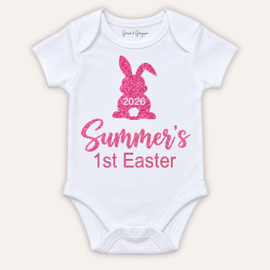 White personalised 1st Easter baby vest with a pink glitter bunny design and 2026 detail, Grace & Grayson