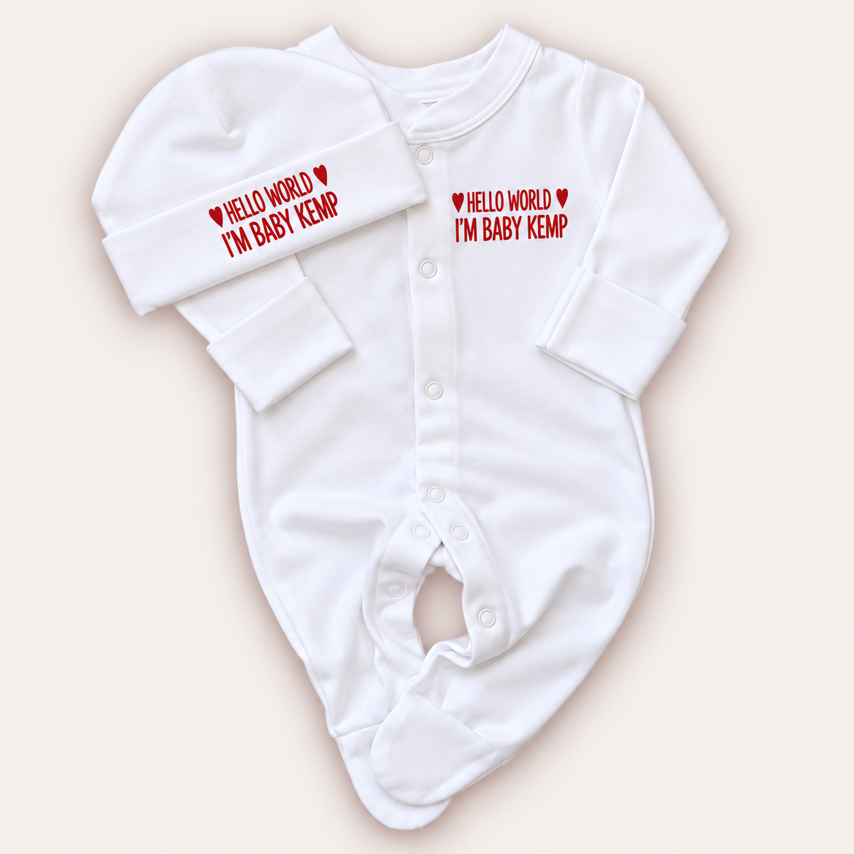 White personalised Hello World baby grow and matching hat with red lettering and heart details, Grace & Grayson