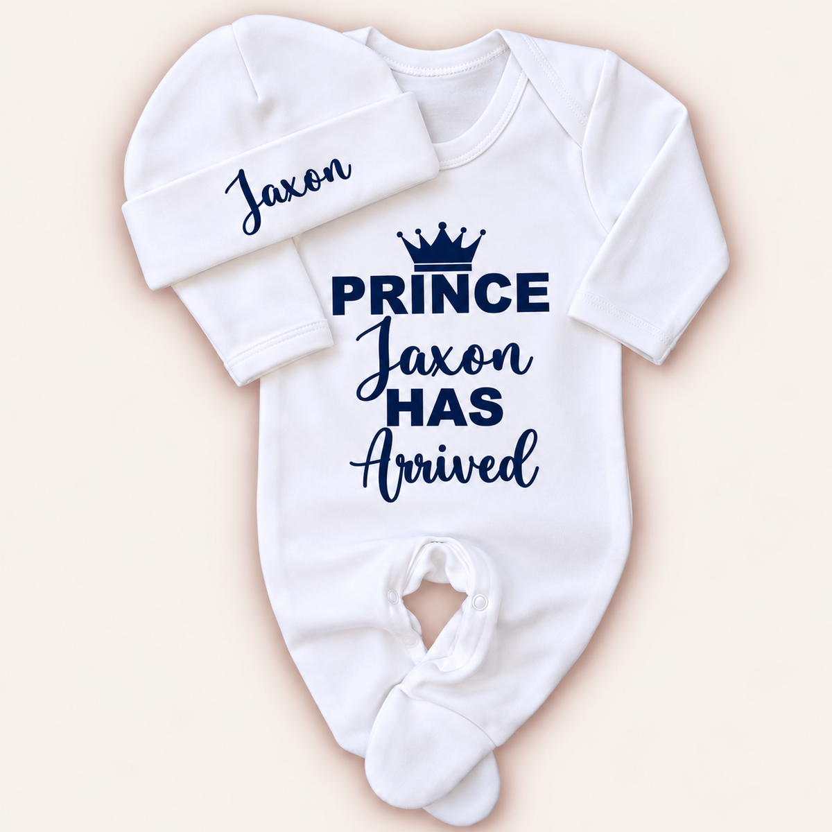 White personalised Prince Has Arrived baby grow and matching hat with navy crown lettering, Grace & Grayson