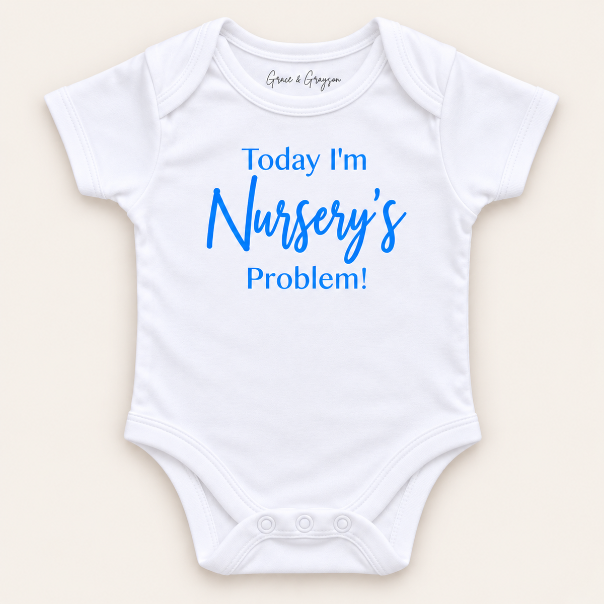 White personalised baby vest with blue lettering reading “Today I’m Nursery’s Problem!”, displayed on a light background, Grace & Grayson.