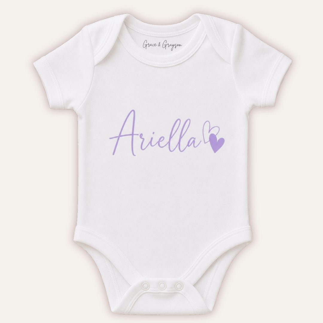 White personalised baby vest with lilac script lettering and a heart Grace & Grayson