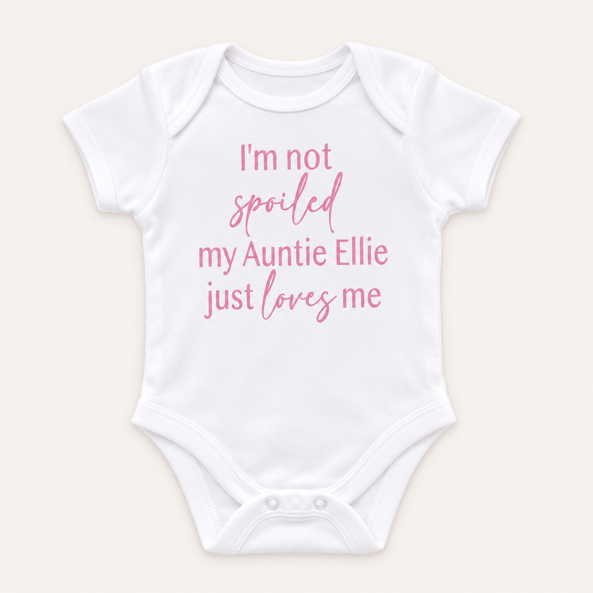 White personalised baby vest with pink lettering featuring a playful message about an auntie, displayed on a light background, Grace & Grayson