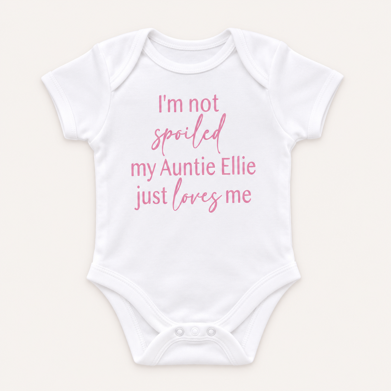 White personalised baby vest with pink lettering featuring a playful message about an auntie, displayed on a light background, Grace & Grayson