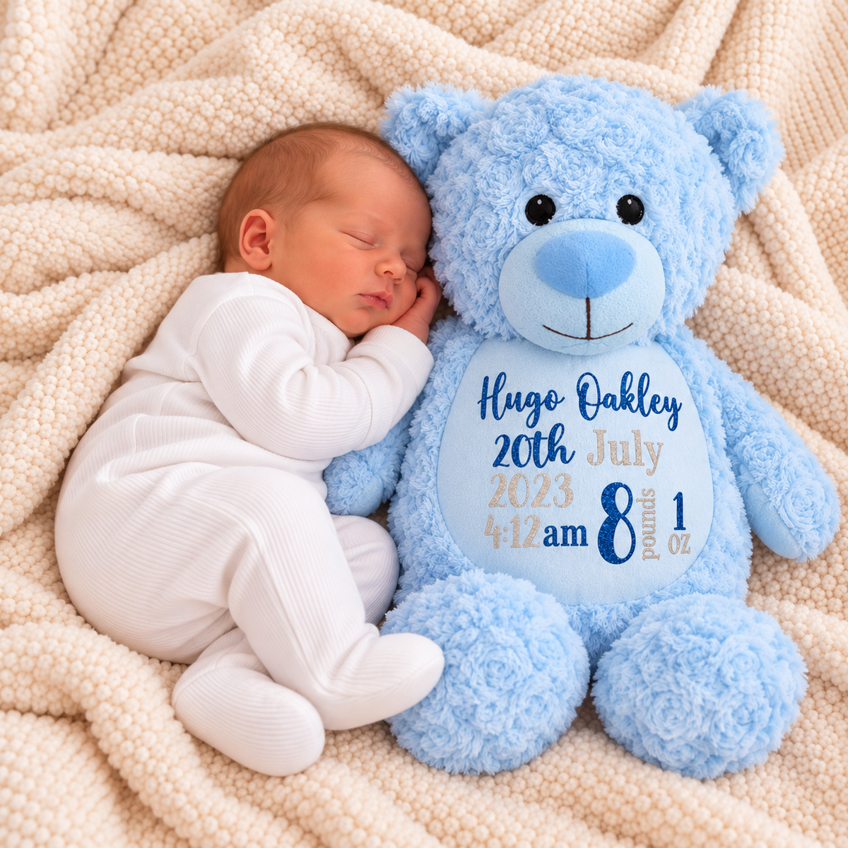 Sleeping newborn in a white sleepsuit beside a fluffy light-blue teddy with a pale-blue muzzle and tummy showing birth details, Grace & Grayson