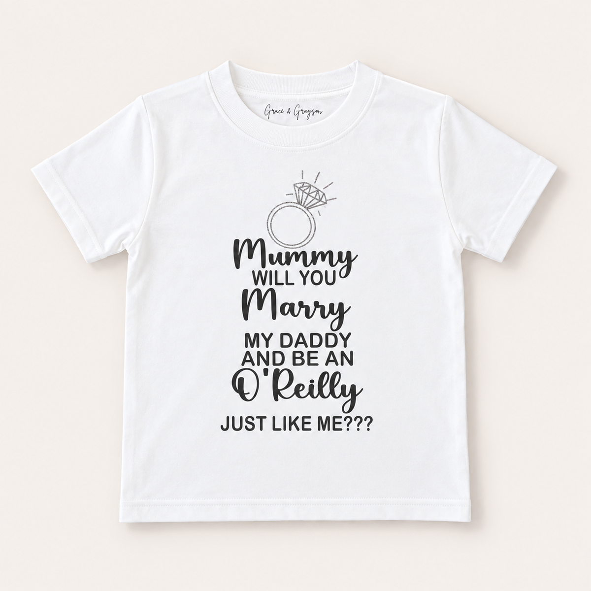 White children’s personalised proposal T-shirt shown at an angle with a ring illustration and family proposal wording, Grace & Grayson