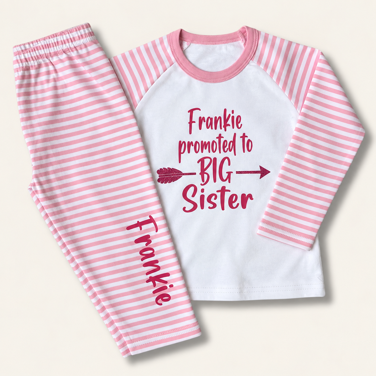 Pink and white striped personalised children’s pyjamas with berry “Promoted to Big Sister” lettering, displayed flat, Grace & Grayson.