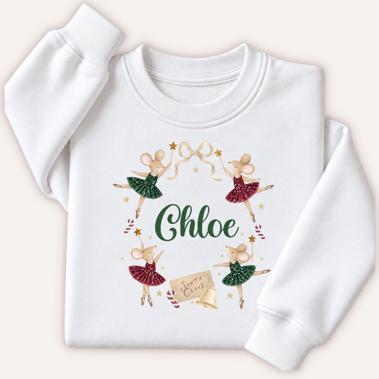 Personalised white Christmas sweatshirt featuring ballerina mice in red and green tutus around a name in green, with candy canes and gold stars. Grace & Grayson.