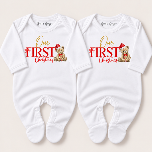 Pair of white footed baby grows with red and gold “Our First Christmas” lettering and teddy bears in Santa hats, Grace & Grayson.
