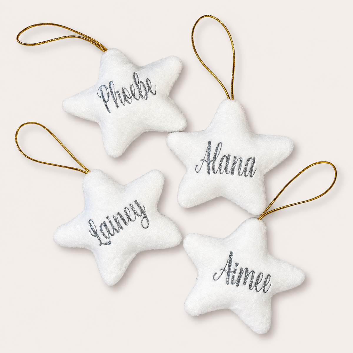  white personalised Christmas star tree decorations with silver glitter lettering, displayed together, Grace & Grayson