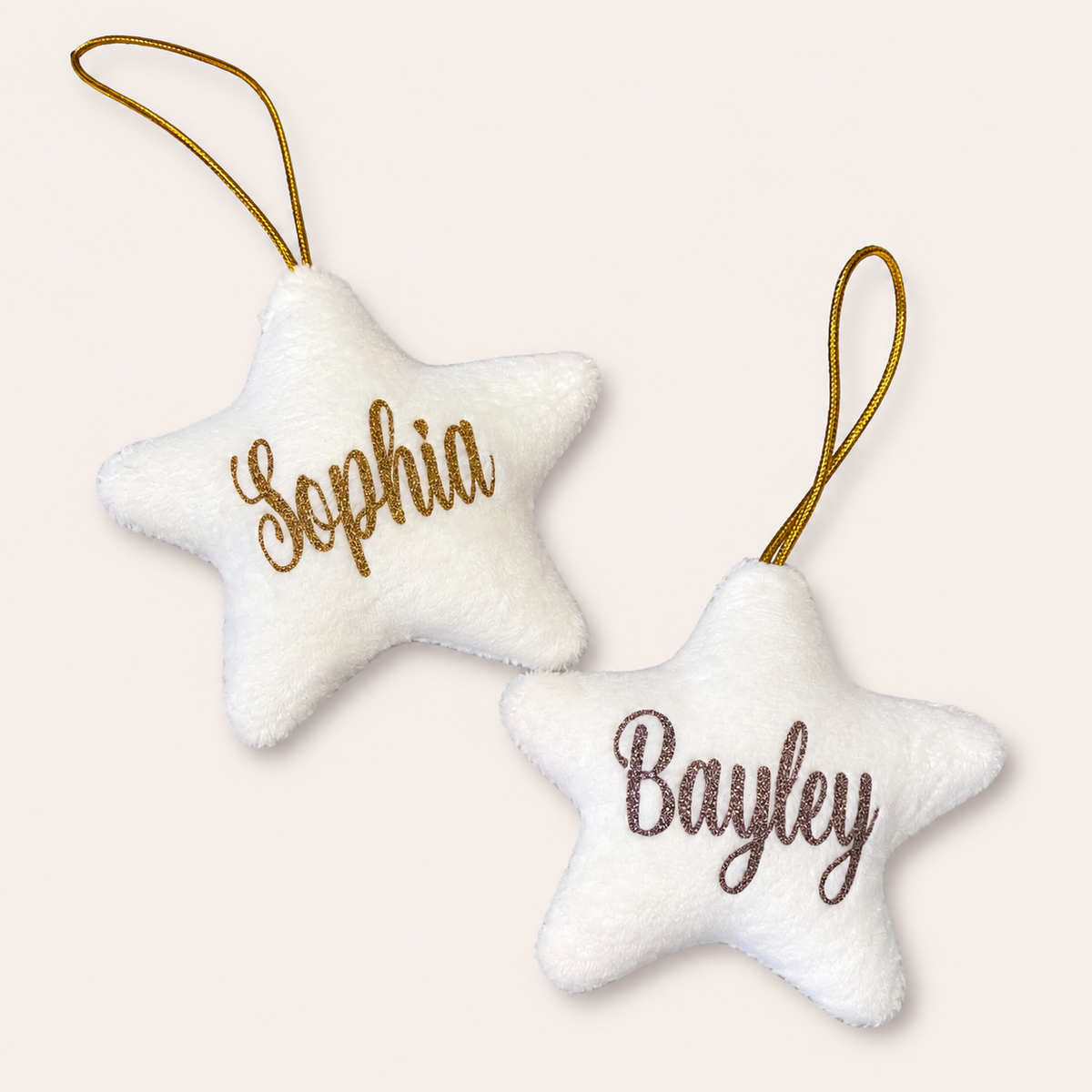Two white personalised Christmas star tree decorations with gold and silver glitter lettering, displayed together, Grace & Grayson