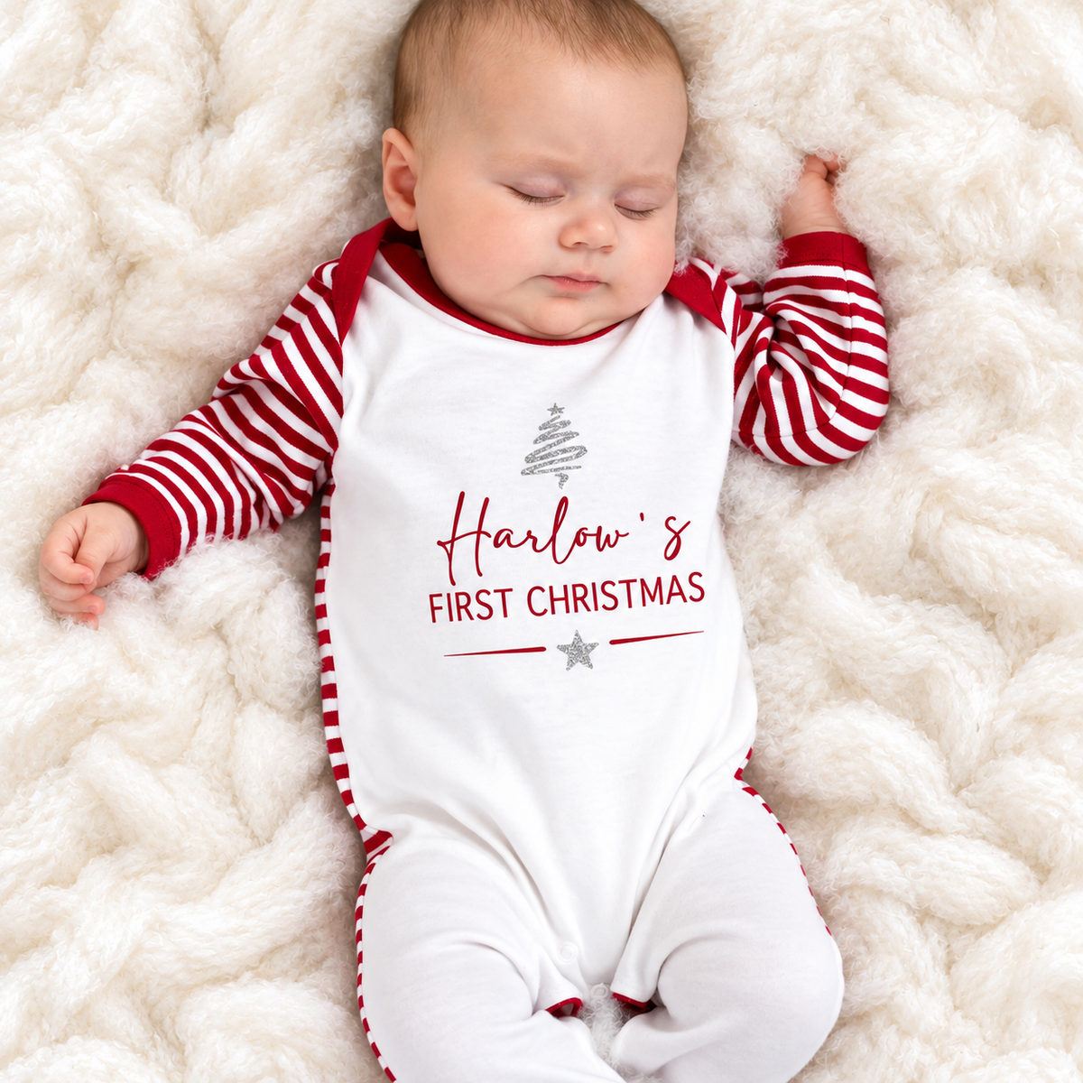 Sleeping baby wearing a personalised First Christmas red and white stripe baby grow with a silver Christmas tree design, Grace & Grayson