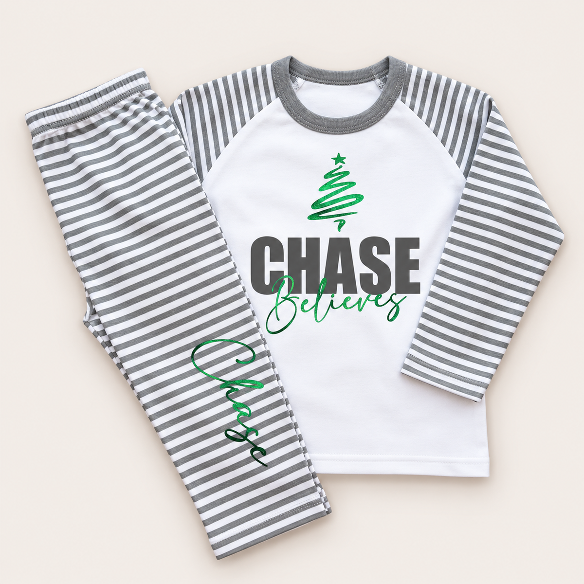 Personalised grey and white stripe Christmas pyjamas with bold name, Christmas tree and “Believes” design by Grace & Grayson