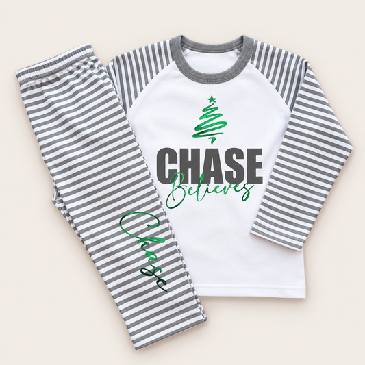 Personalised grey and white stripe Christmas pyjamas with bold name, Christmas tree and “Believes” design by Grace & Grayson