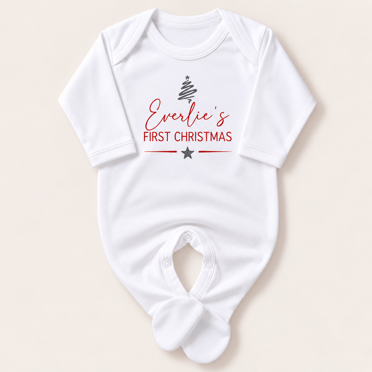 White footed baby grow with a silver Christmas tree, red First Christmas lettering and silver star, Grace & Grayson.