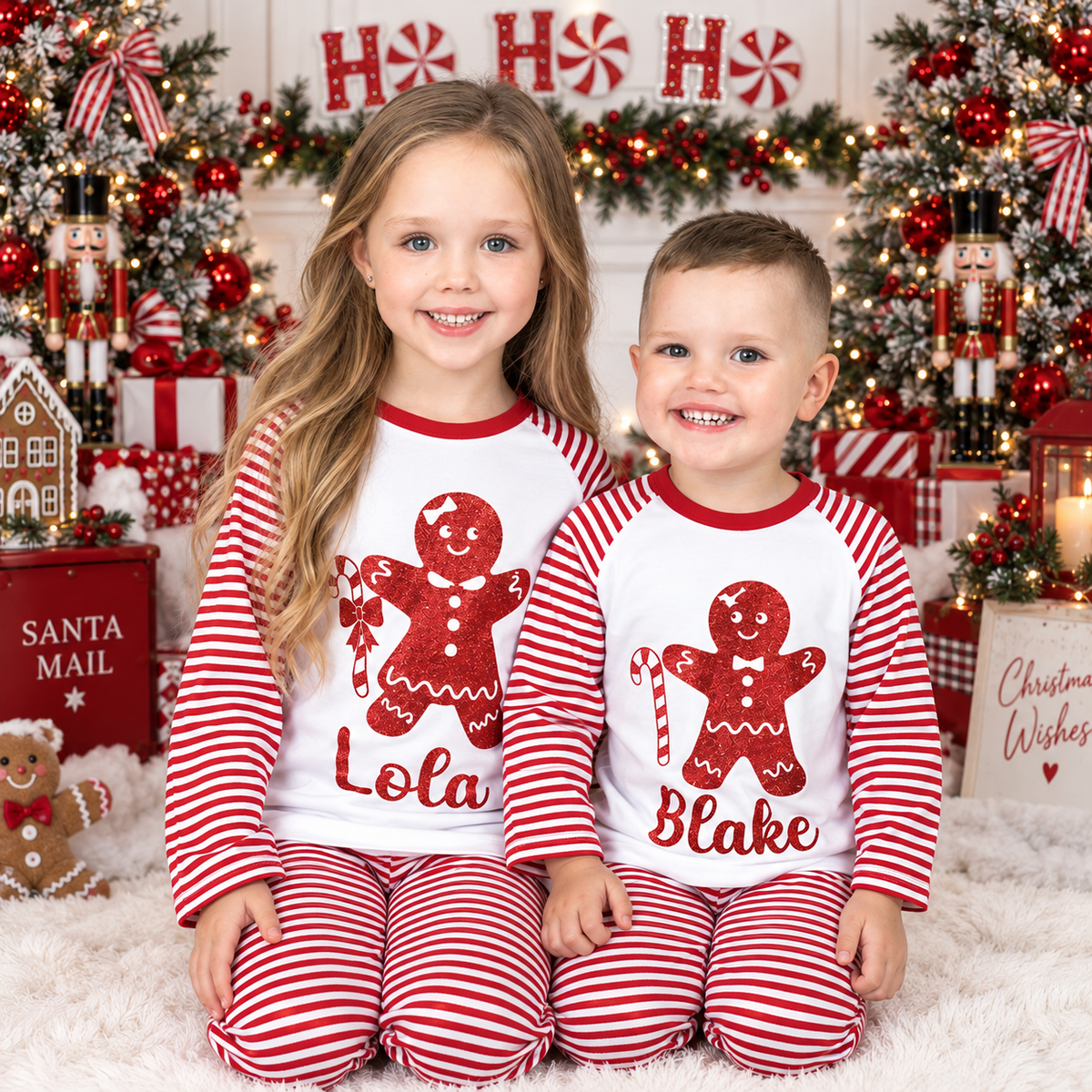 Two children wearing personalised red and white striped gingerbread man Christmas pyjamas in a festive room by Grace & Grayson