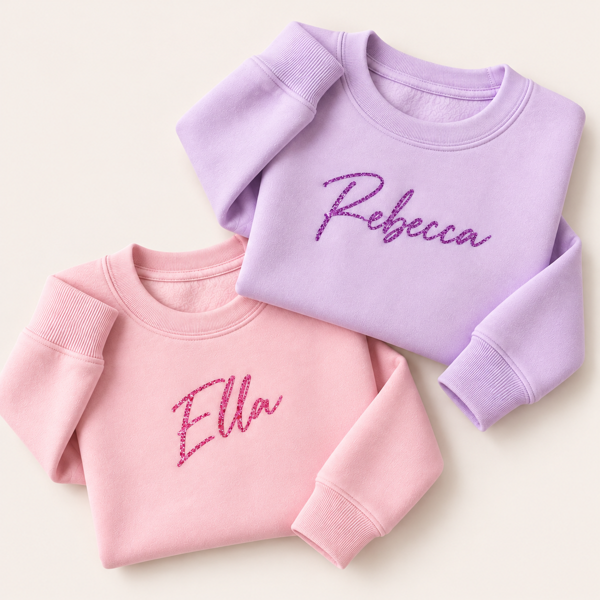 Lilac and pink personalised sweatshirts with purple and pink glitter script names, folded together | Grace & Grayson