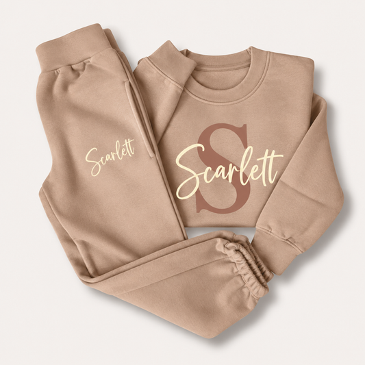 Warm taupe personalised sweatshirt and joggers with a brown initial and cream script name, laid flat, Grace & Grayson